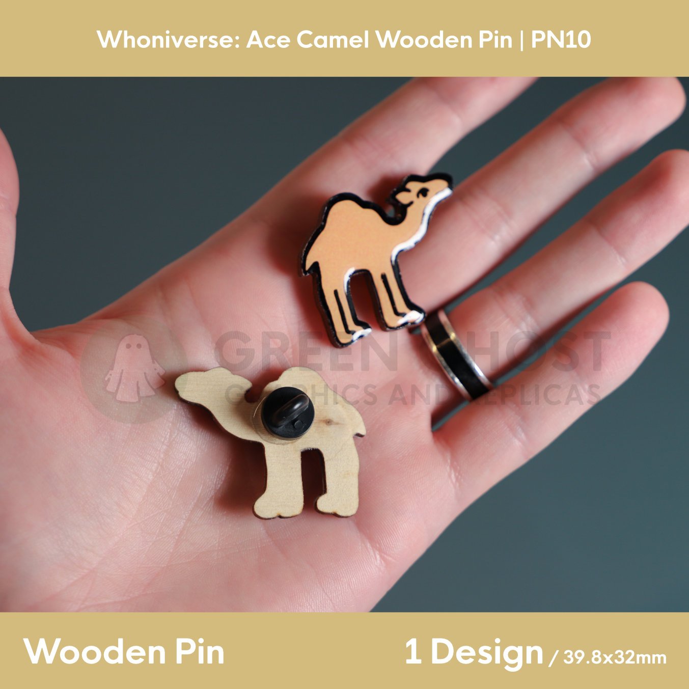 A close‑up of two wooden camel pins held in a hand, showing the front painted design and the back with a metal clasp.