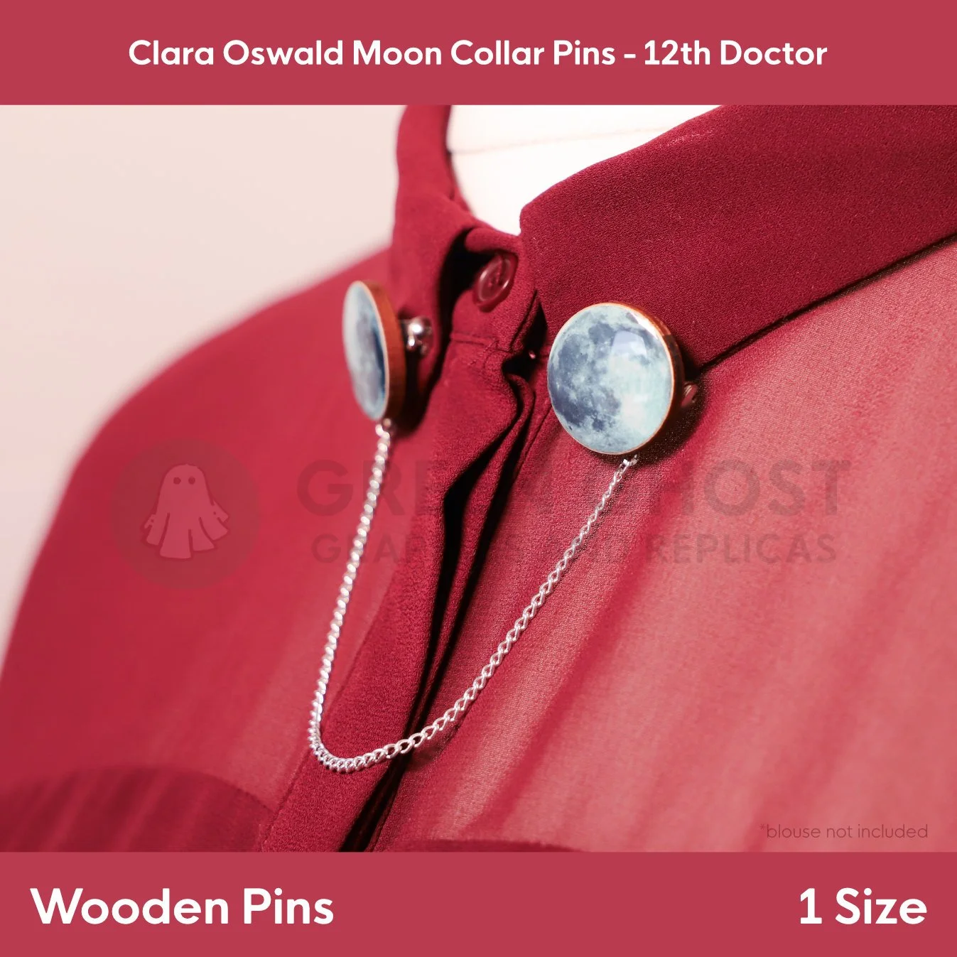 Two moon‑patterned circular pins attached to a red blouse collar and linked with a delicate silver chain.