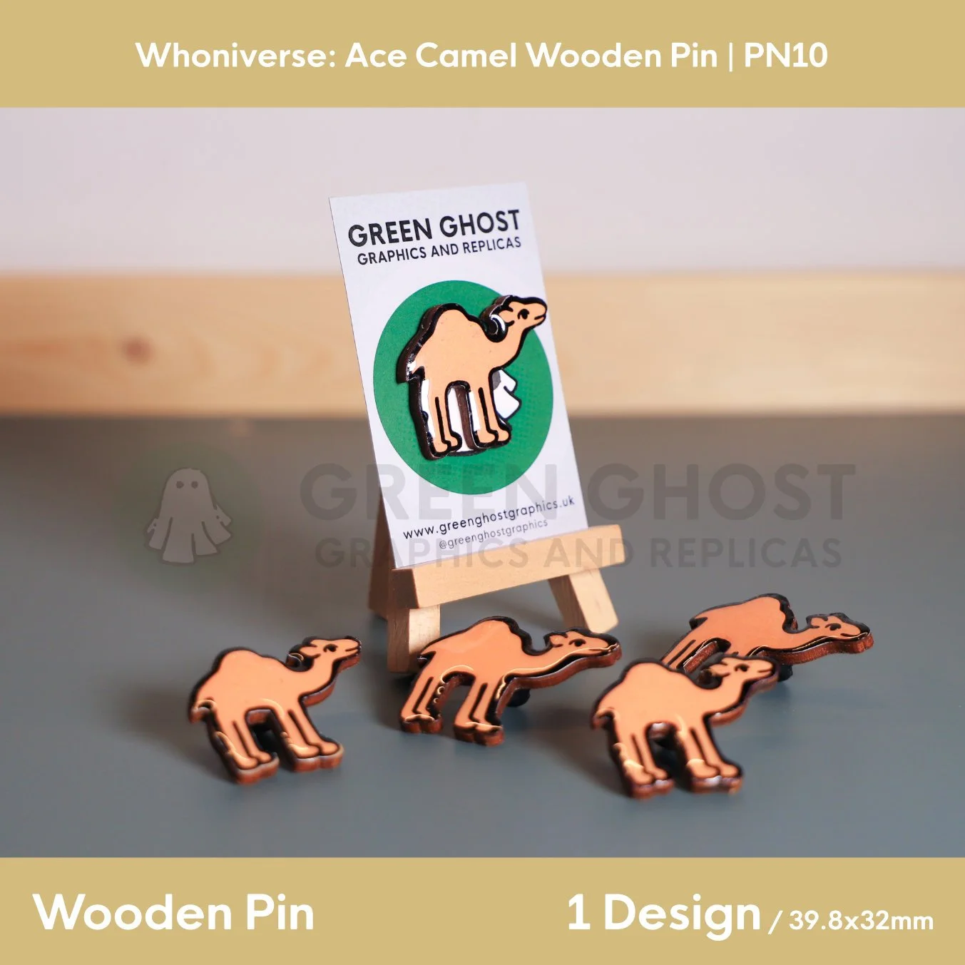 Several wooden camel pins displayed on a flat surface, with one mounted on a branded backing card on a wooden easel.