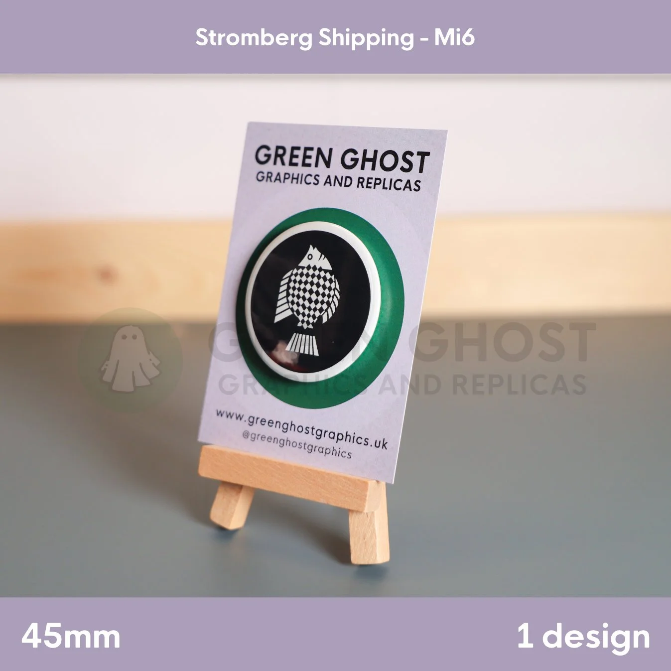 A circular badge featuring a black and white patterned fish mounted on a branded card on a wooden easel.