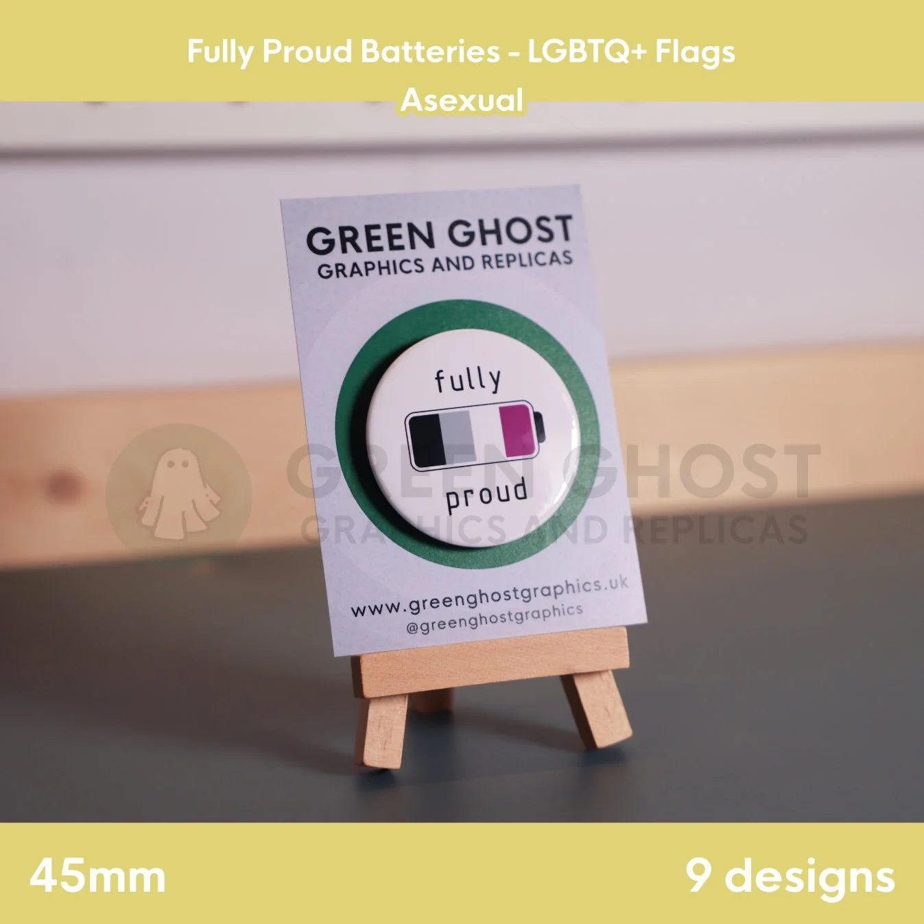 A round badge with an black, grey, white, and purple battery design displayed on a branded backing card on a wooden easel.