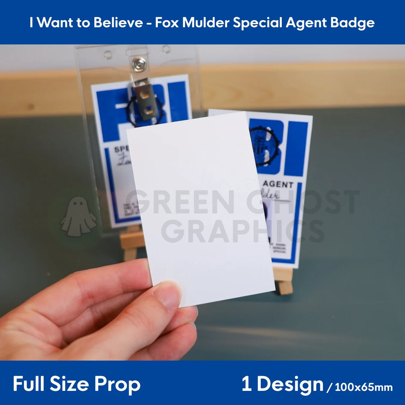 A plain white rectangular card shown from the reverse side while being held in a hand, with FBI badge displays visible in the background.