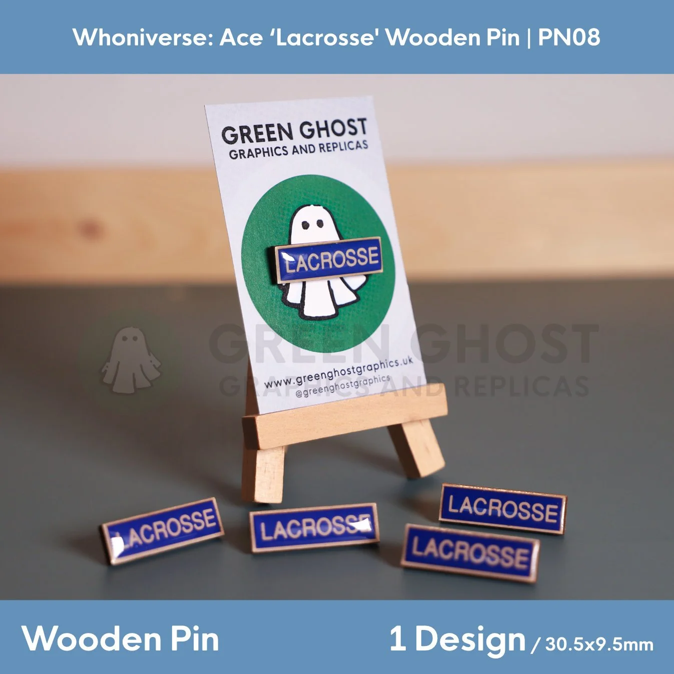 A rectangular wooden “LACROSSE” pin attached to a branded backing card featuring a ghost logo, displayed on a small wooden easel with additional pins arranged around it.