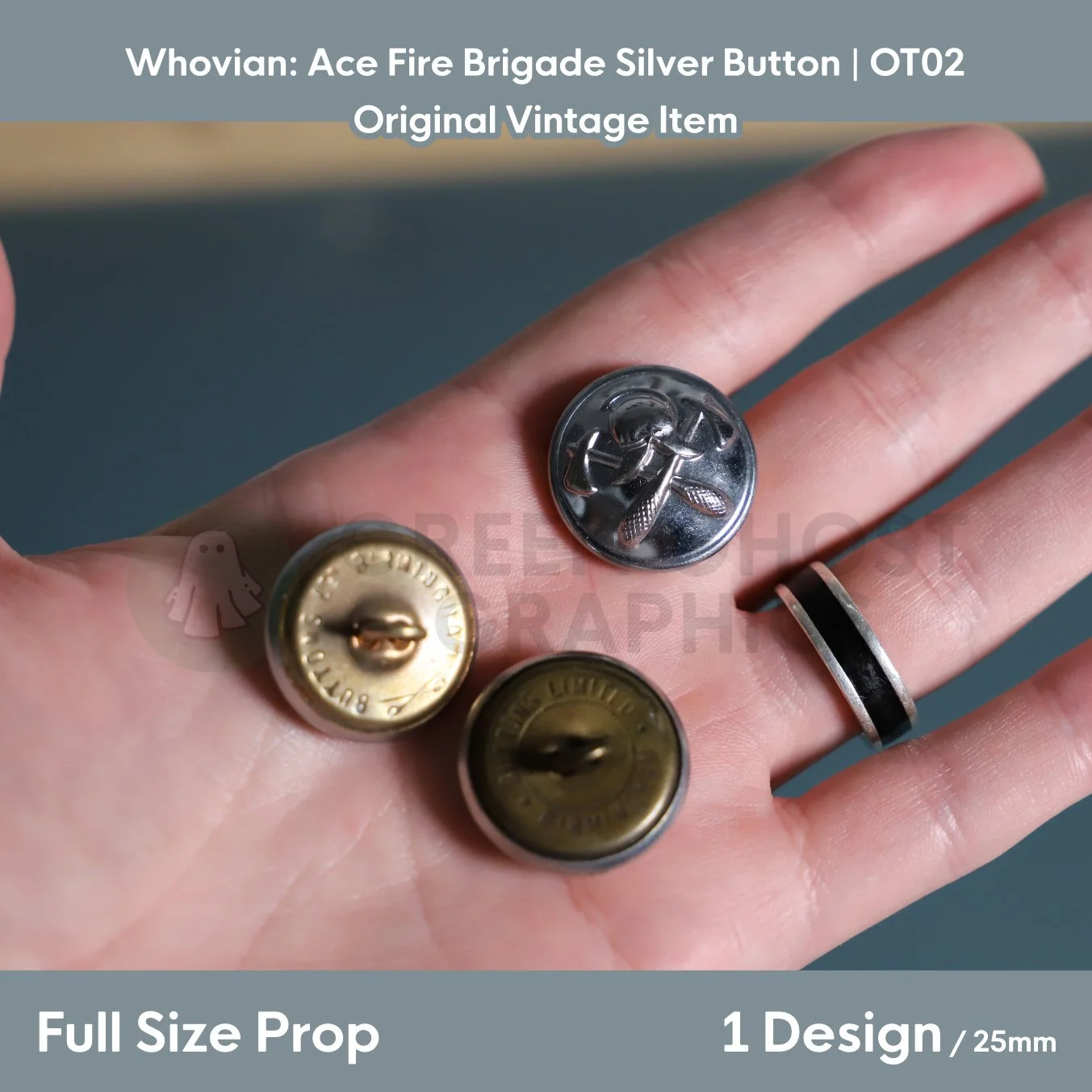 A round silver fire brigade button with crossed axes and helmet detail shown in a hand alongside two brass‑coloured reverse views.