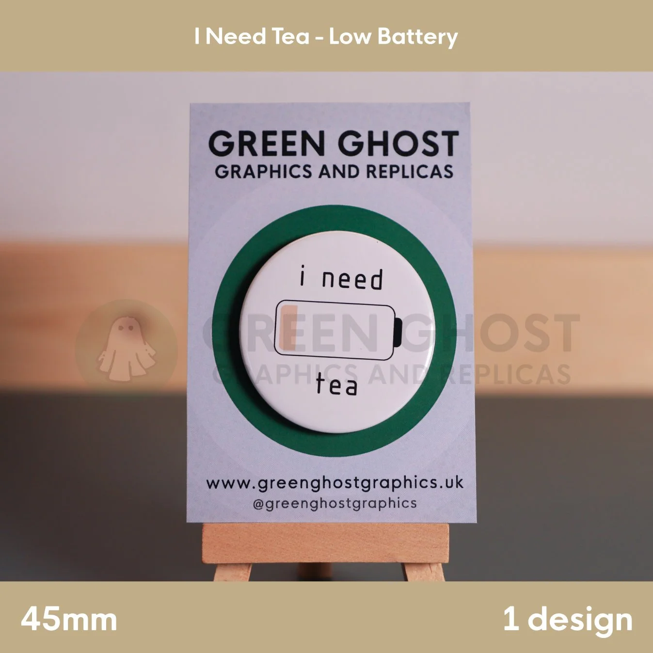A circular white badge with “i need tea” text beside a low‑battery icon mounted on a branded backing card.