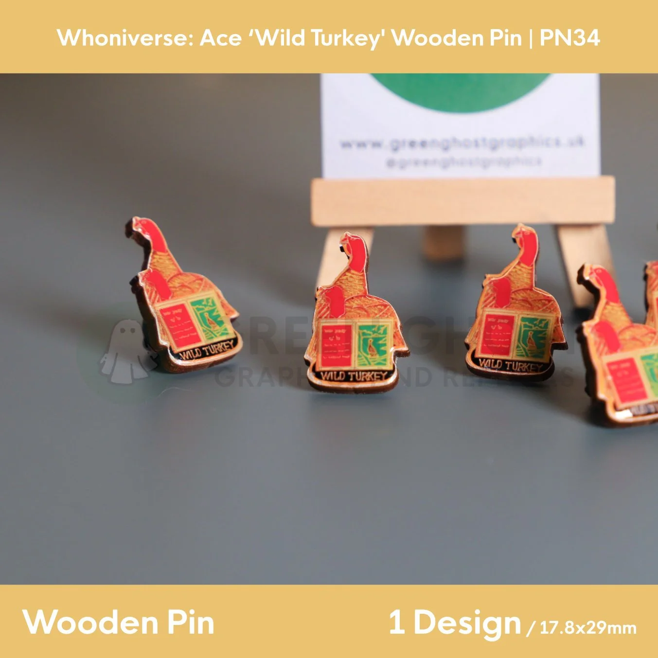 Several wooden pins shaped like two turkeys and open book arranged on a smooth grey surface, with a wooden easel holding a branded backing card in the background.