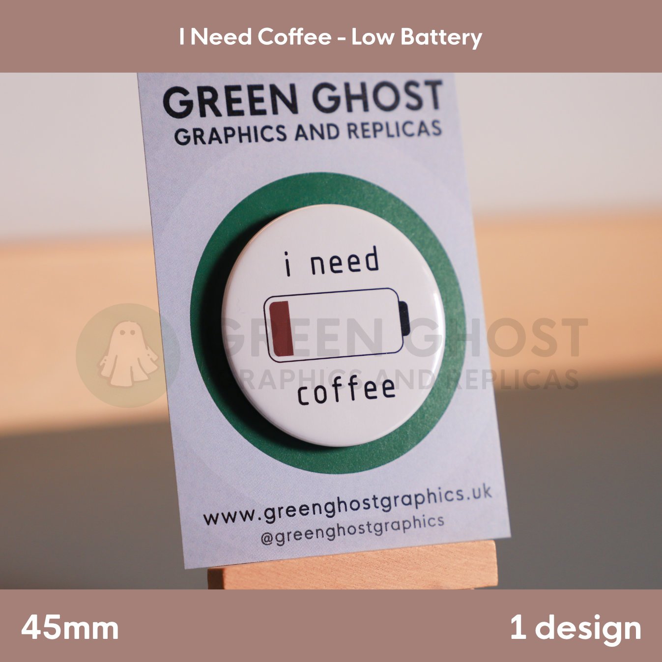 A round white badge featuring a low‑battery icon and the phrase “i need coffee” attached to a branded display card.