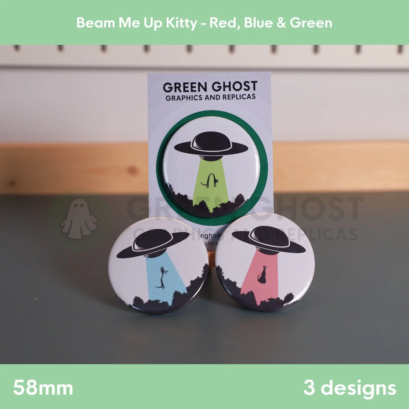 Three round badges with coloured UFO beams lifting a cat arranged on a flat surface with one on a backing card.