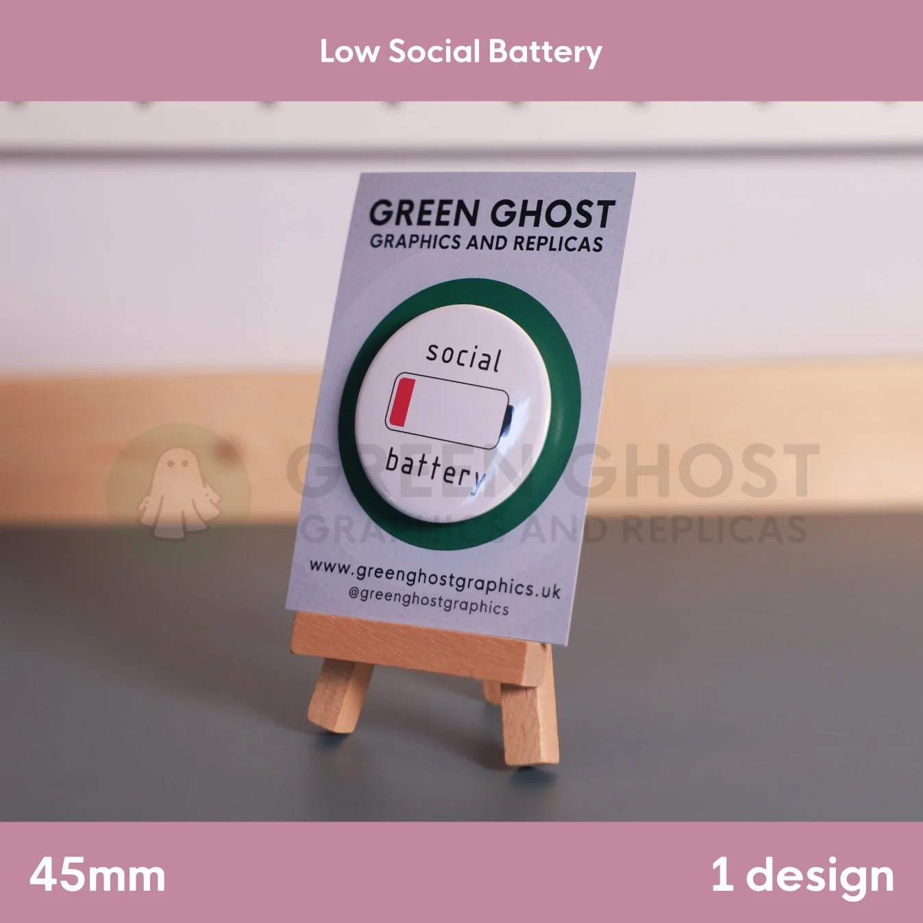 A round badge, red low‑battery icon, and “social battery” wording mounted on a branded backing card.