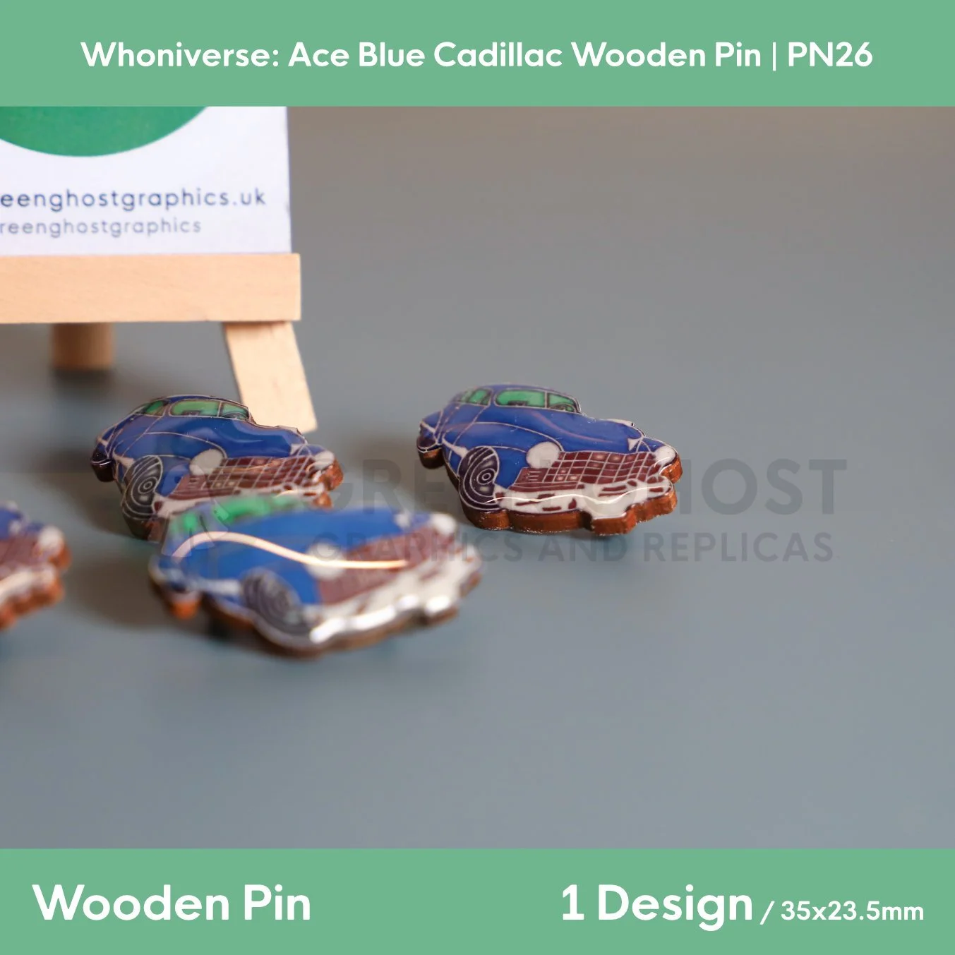A stylised blue Cadillac wooden pin displayed on a branded backing card featuring a green circular background, set on a wooden easel with additional pins visible behind.