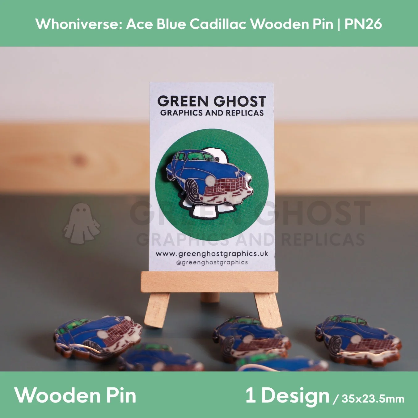 A wooden pin shaped like a blue Cadillac car attached to a branded backing card on a wooden easel, with several identical pins arranged on the surface in front.