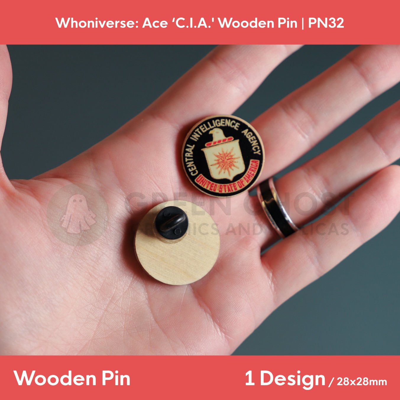 A close‑up of two circular “Central Intelligence Agency, United States of America” wooden pins held in a hand, showing the front text design and the back with a clasp attachment.