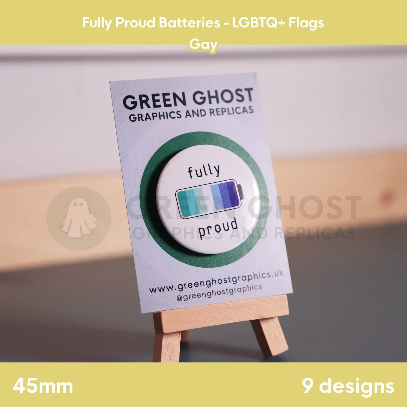 A round badge with teal, blue, and purple battery stripes displayed on a branded backing card on a wooden easel.