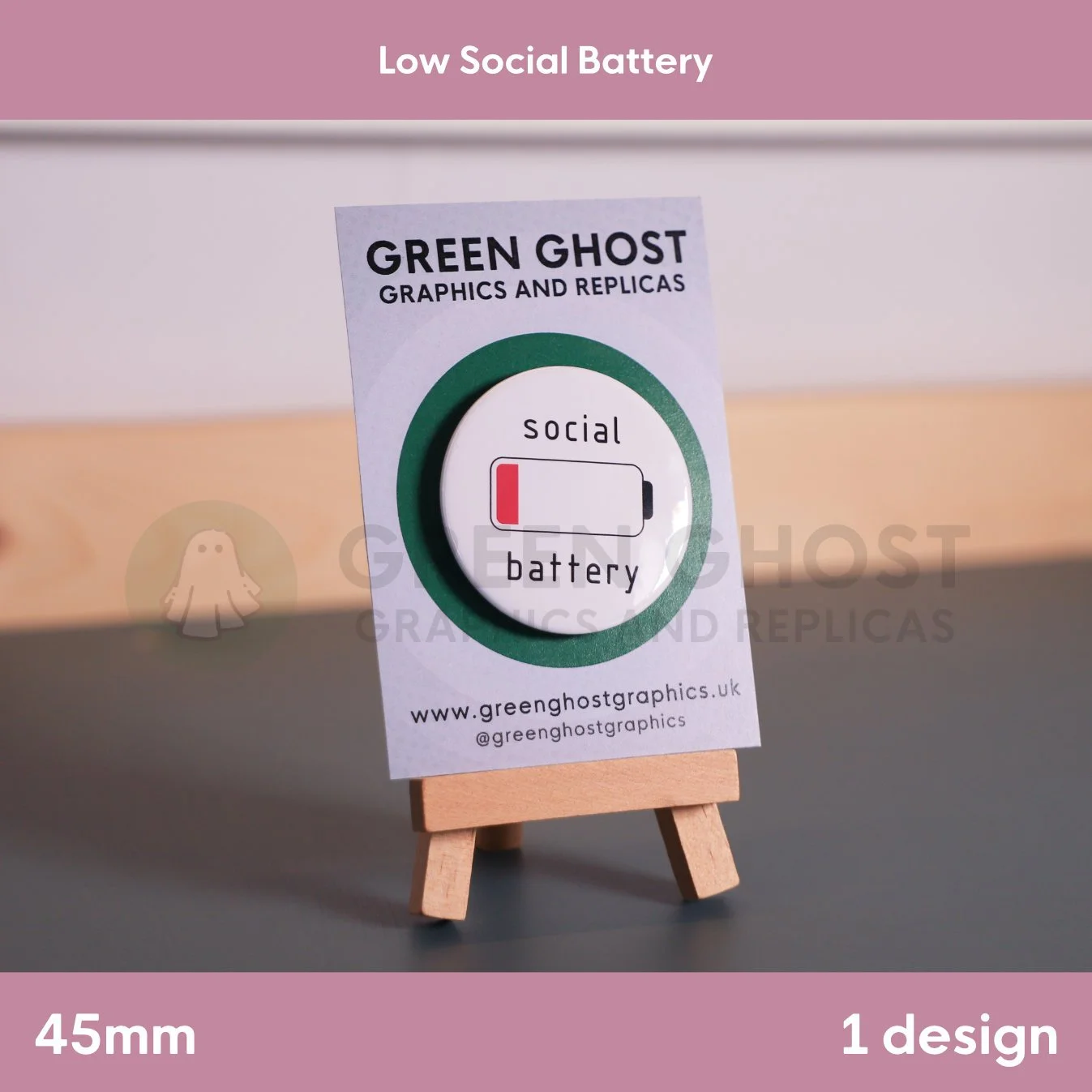 A round badge featuring a red‑bar battery icon and the text “social battery” displayed on a wooden easel with a branded card.