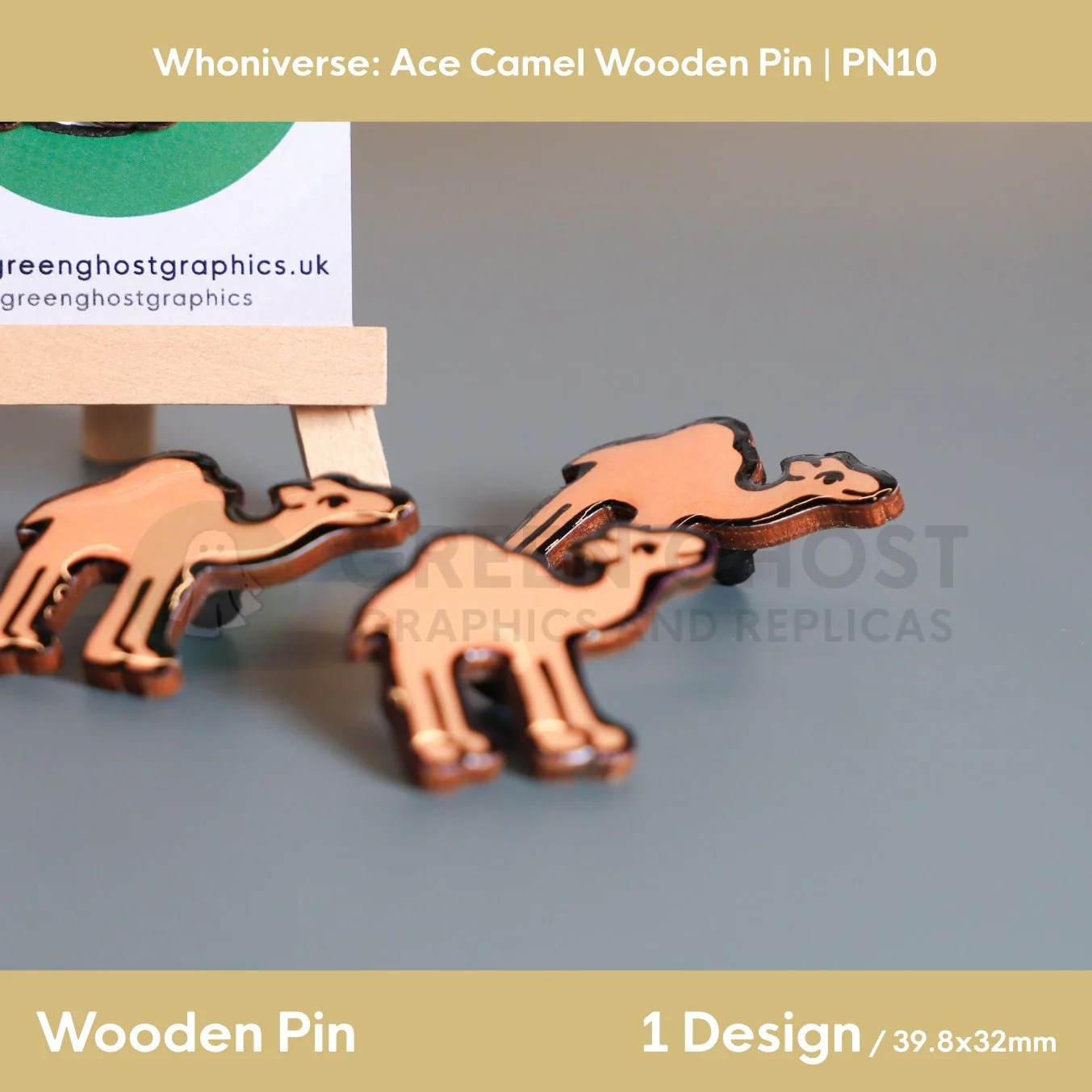 Three wooden camel pins arranged on a smooth surface, with a branded backing card on a wooden easel positioned behind them.
