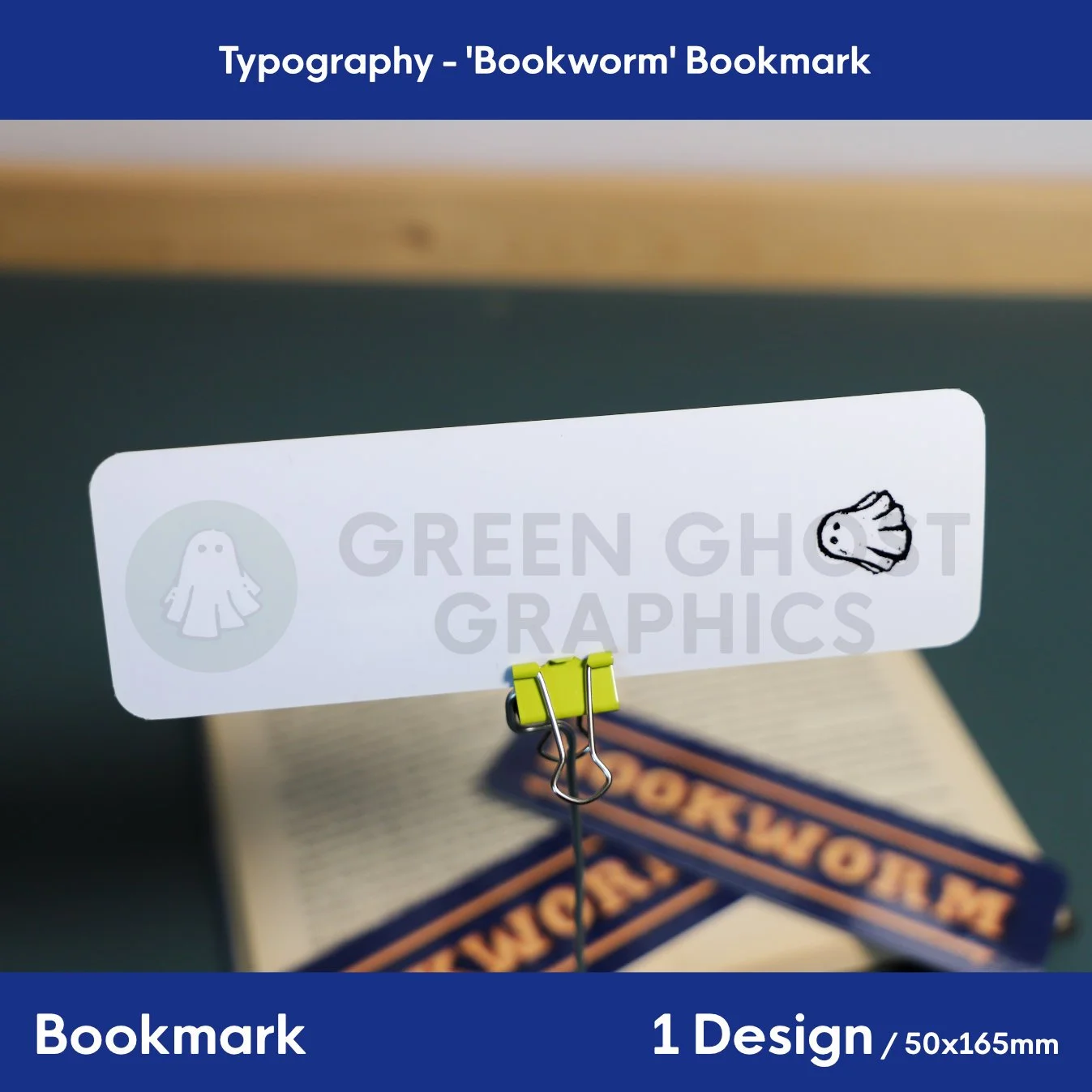 Rear view of the bookmark showing a clean plain white with a back stamp design of a small ghost logo, shown against a blurred book background.