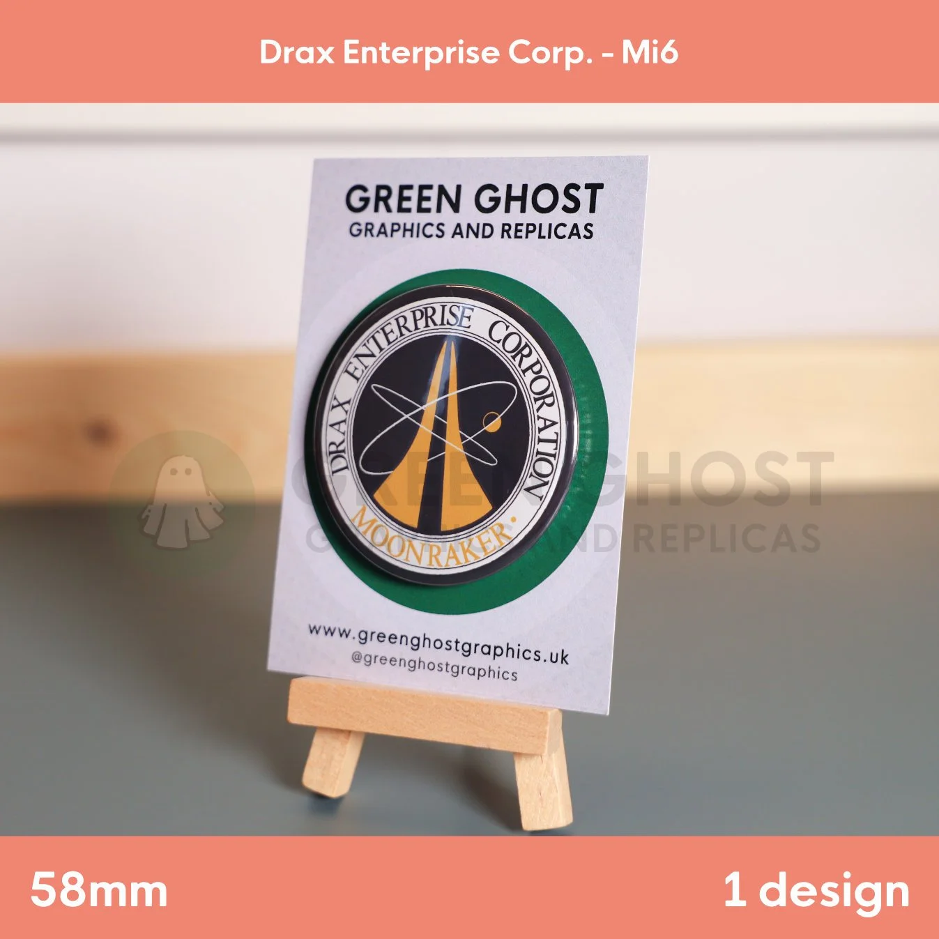 A circular badge with orange and black “DRAX ENTERPRISE CORPORATION MOONRAKER” text and a rocket‑orbit emblem mounted on a branded card on a wooden easel.