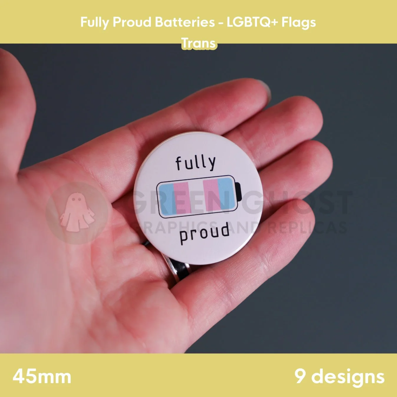 A round badge with a light blue, pink, and white battery design held in a hand against a grey background.