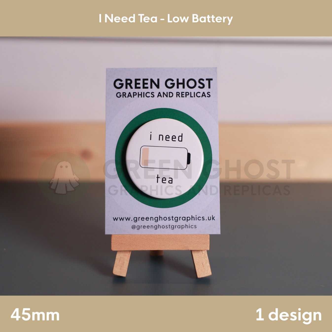 A round badge with a nearly empty battery icon and the words “i need tea” displayed on a wooden easel with a branded card.