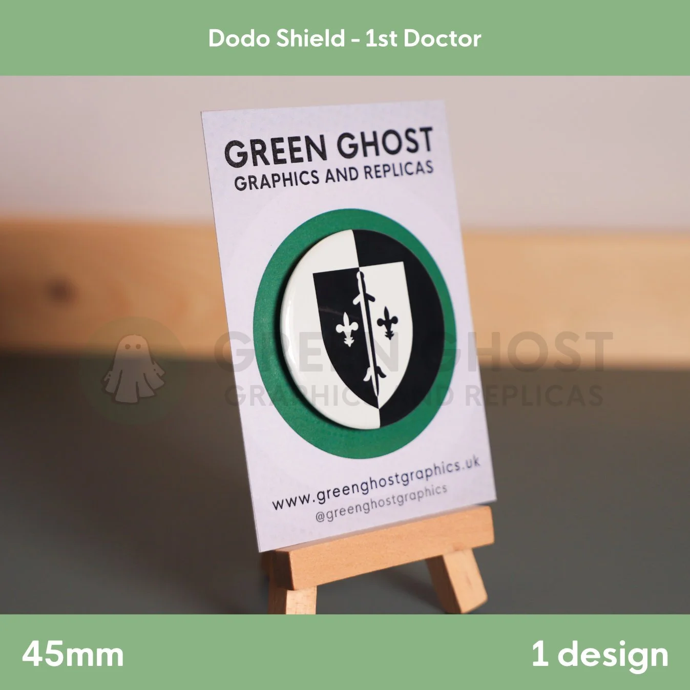 A circular badge featuring a black and white shield with fleur‑de‑lis symbols displayed on a branded card on a wooden easel.