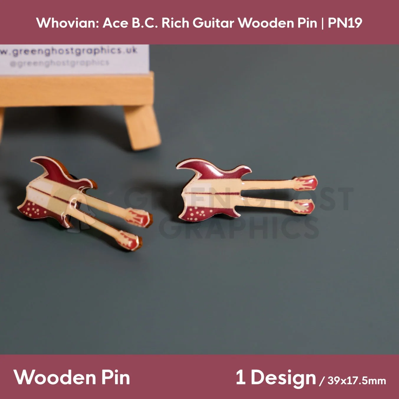 Two brown and beige guitar‑shaped wooden pins with twin necks displayed side by side on a dark grey surface in front of a branded stand.
