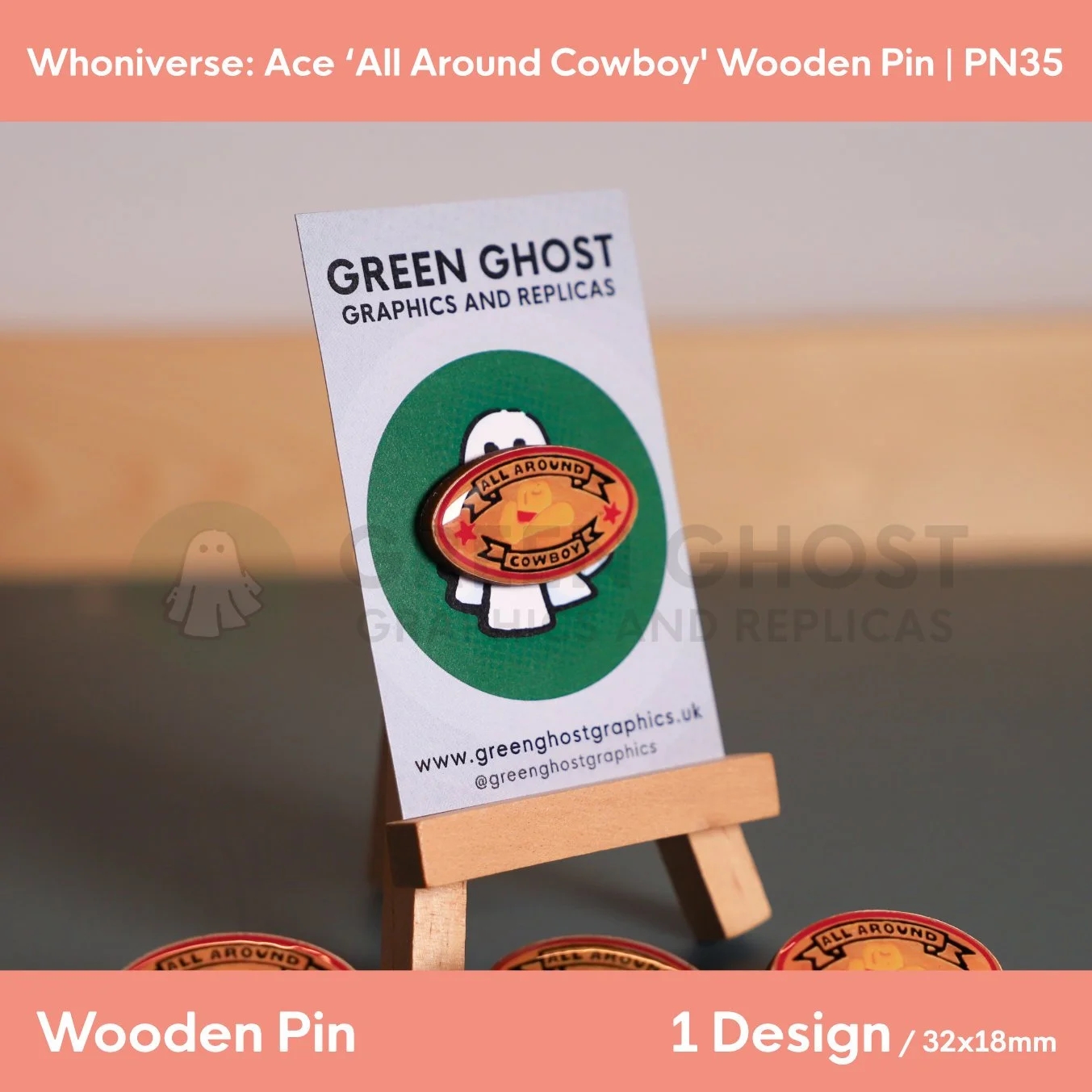 An oval wooden pin featuring coloured text and cowboy hat motif “ALL AROUND COWBOY” with a number of other pins in the background.