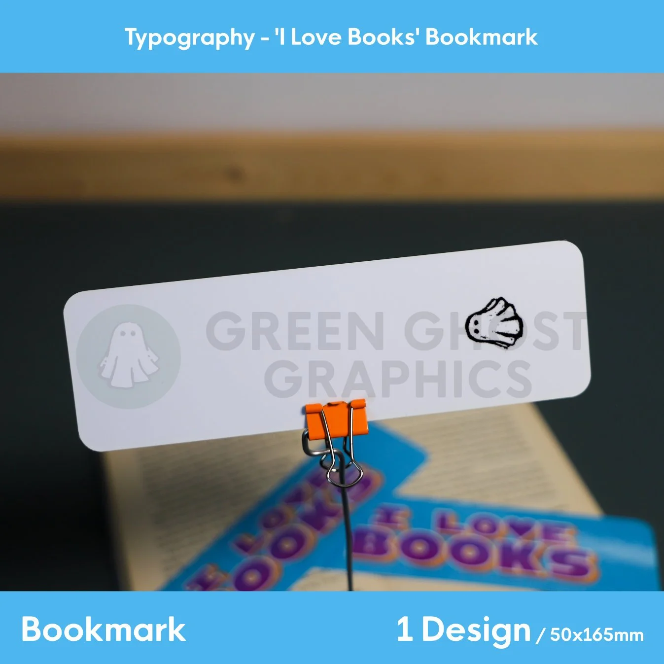 Rear view of the bookmark showing a clean white with a back stamp design of a small ghost logo, shown against a blurred book background.