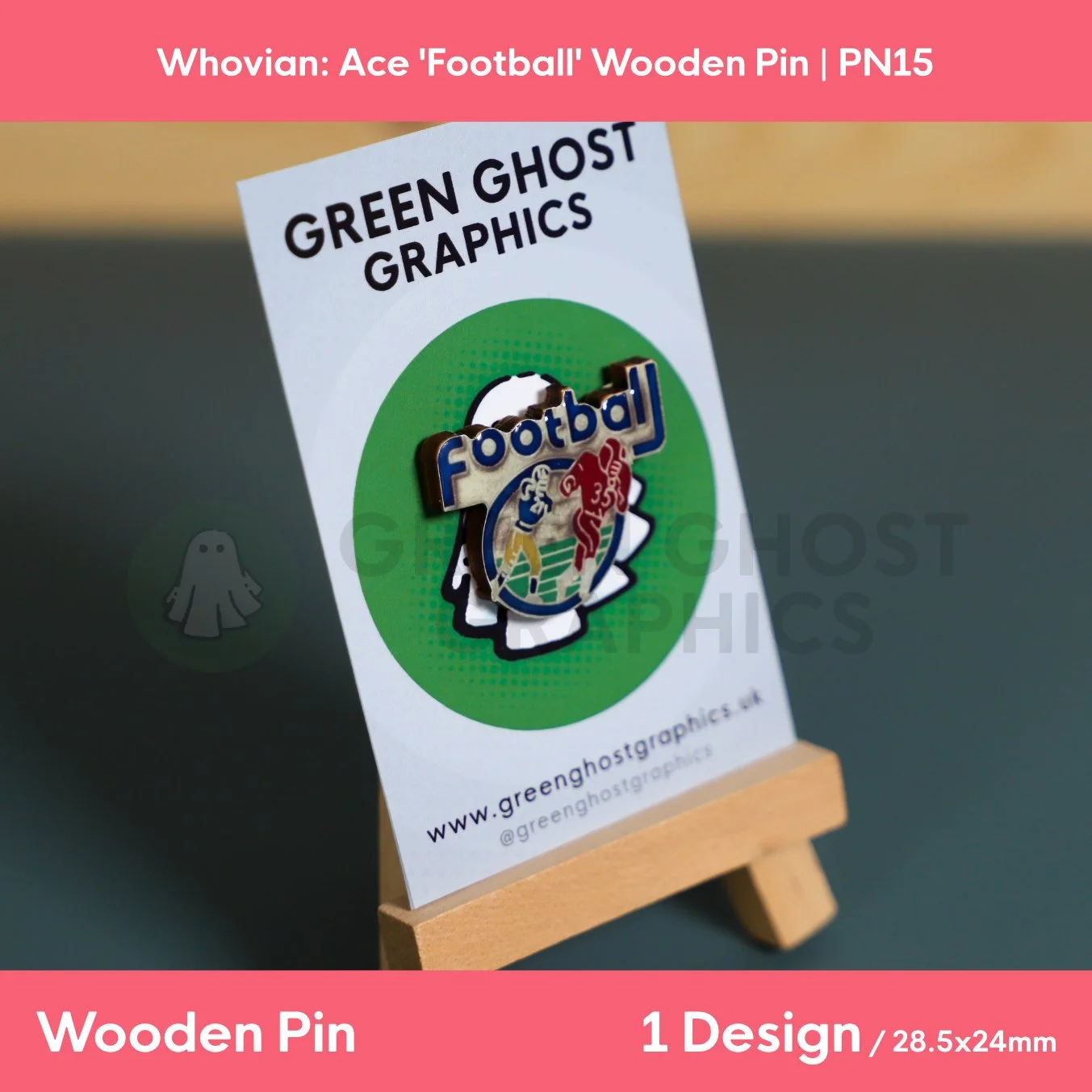 A football‑shaped wooden pin featuring blue “Football” lettering and colourful player artwork mounted on a Green Ghost Graphics display card on a wooden easel.