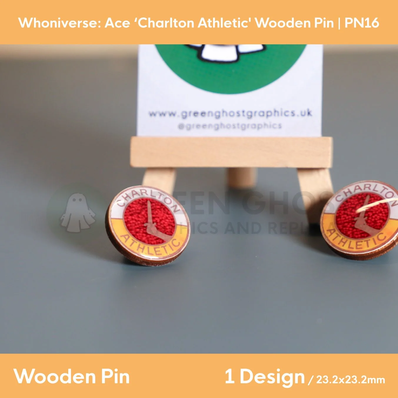 Two circular wooden “Charlton Athletic” pins displayed on a grey surface, with a branded backing card on a wooden easel positioned behind them.