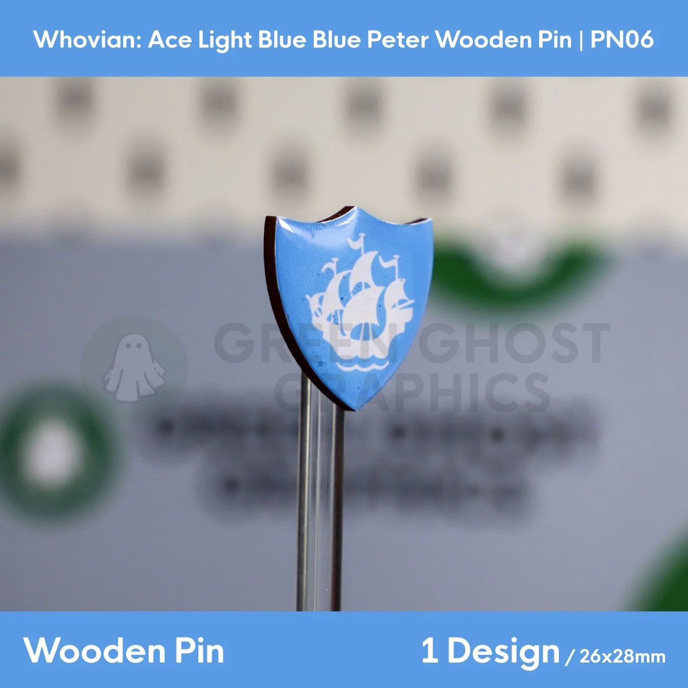 A blue shield‑shaped wooden pin featuring a white sailing ship design displayed on a Green Ghost Graphics card with three matching pins arranged below.