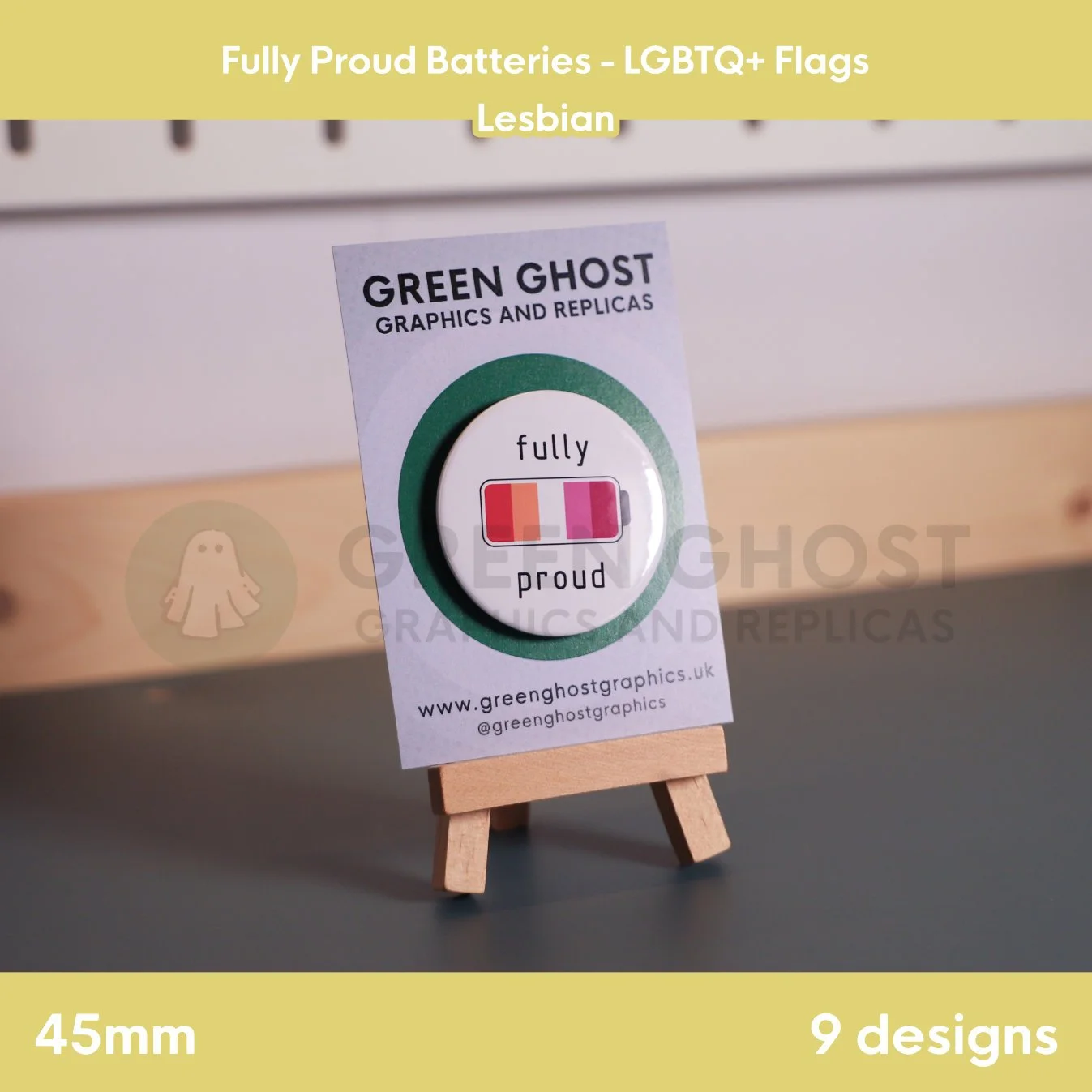 A round badge with an orange, white, pink, and red battery design displayed on a branded backing card on a wooden easel.
