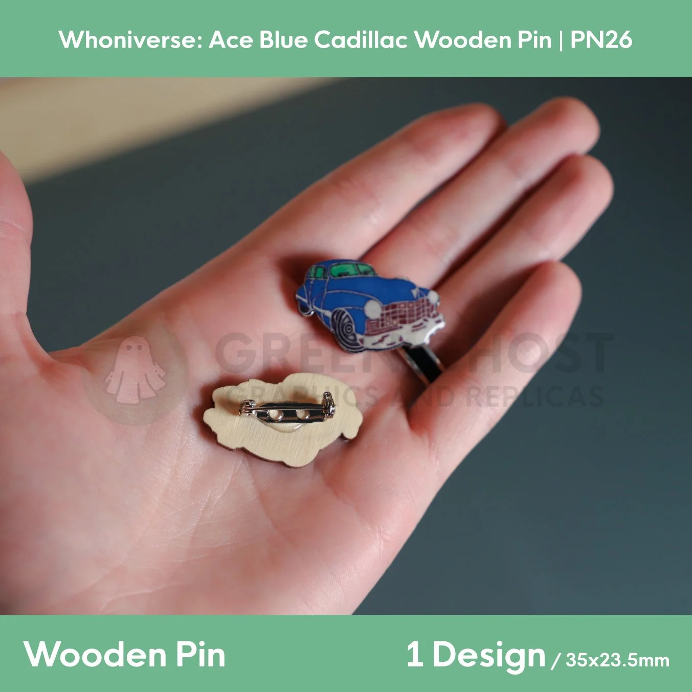 A close‑up of two wooden Cadillac pins held in a hand, showing the detailed blue car design on the front and the metal clasp on the back.