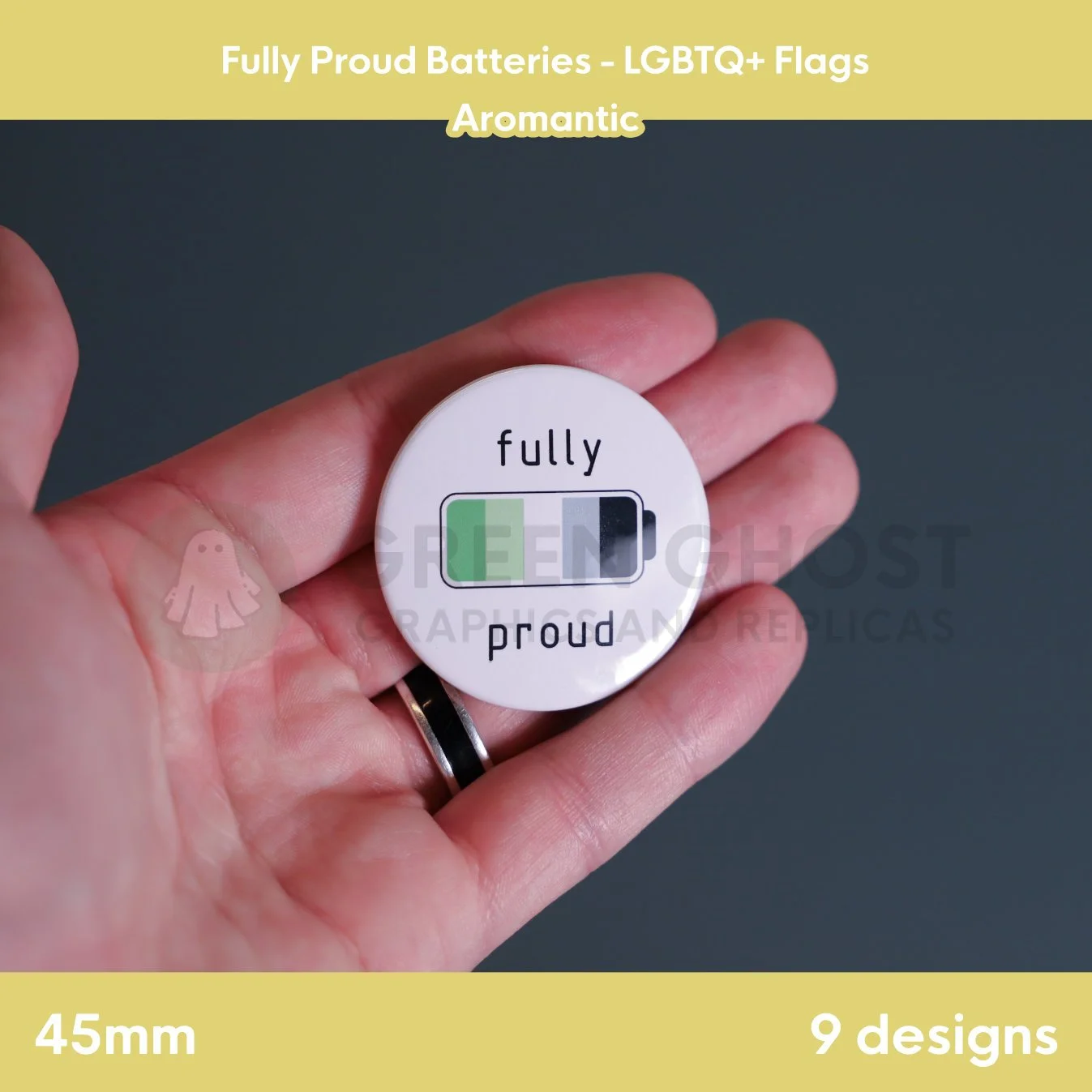 A round badge with a green, light green, white, grey, and black battery design held in a hand against a grey background.