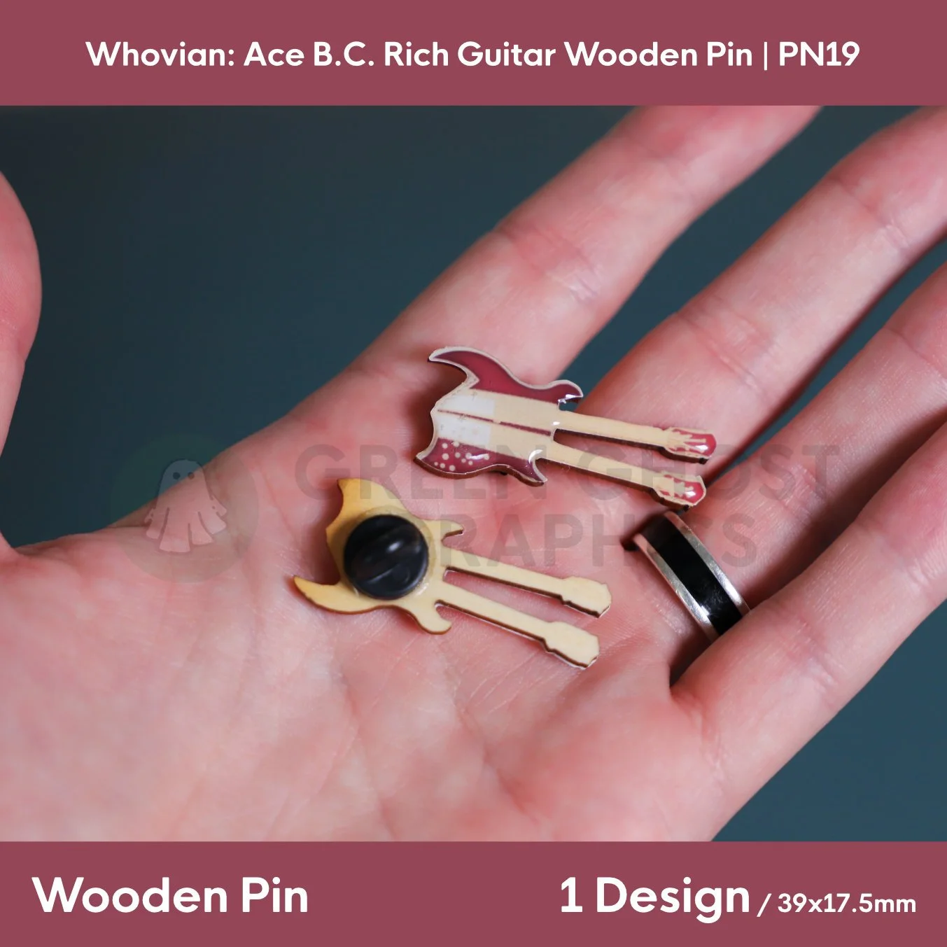 A double‑neck guitar wooden pin in brown and beige tones displayed in a hand alongside the natural wood reverse with a black rubber clasp.