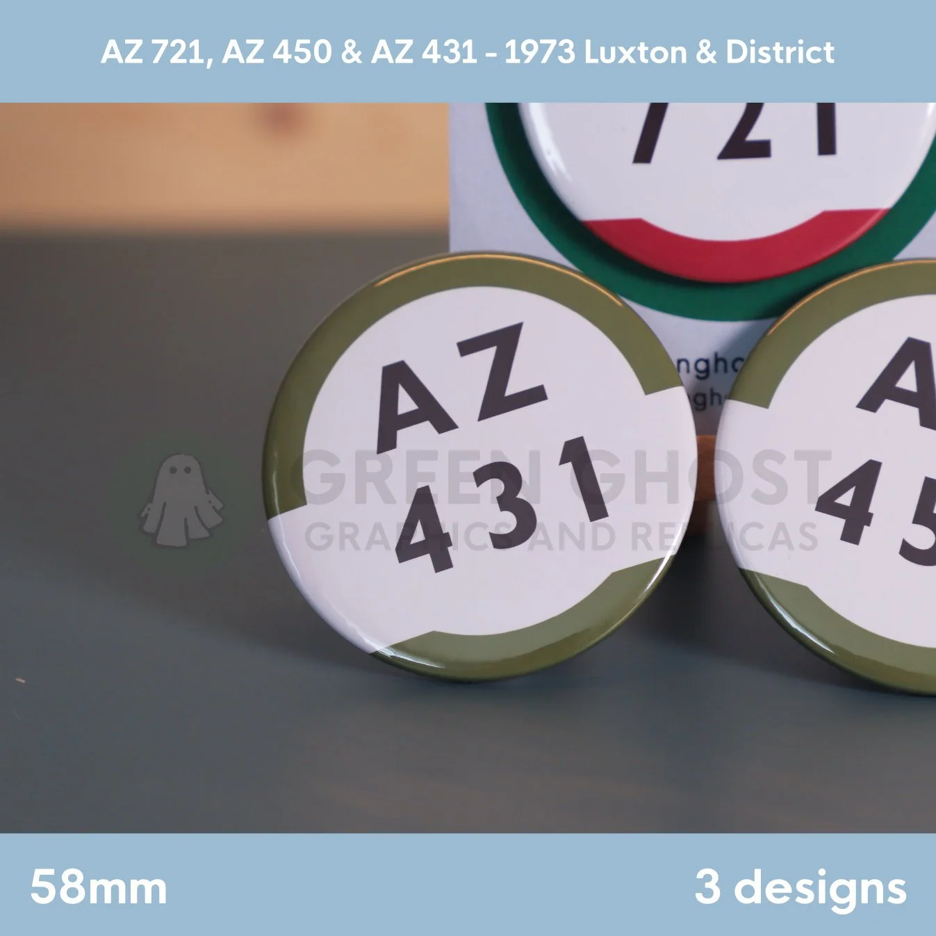 Three round badges with white centres, coloured borders, and black route codes displayed on an easel and nearby surface.