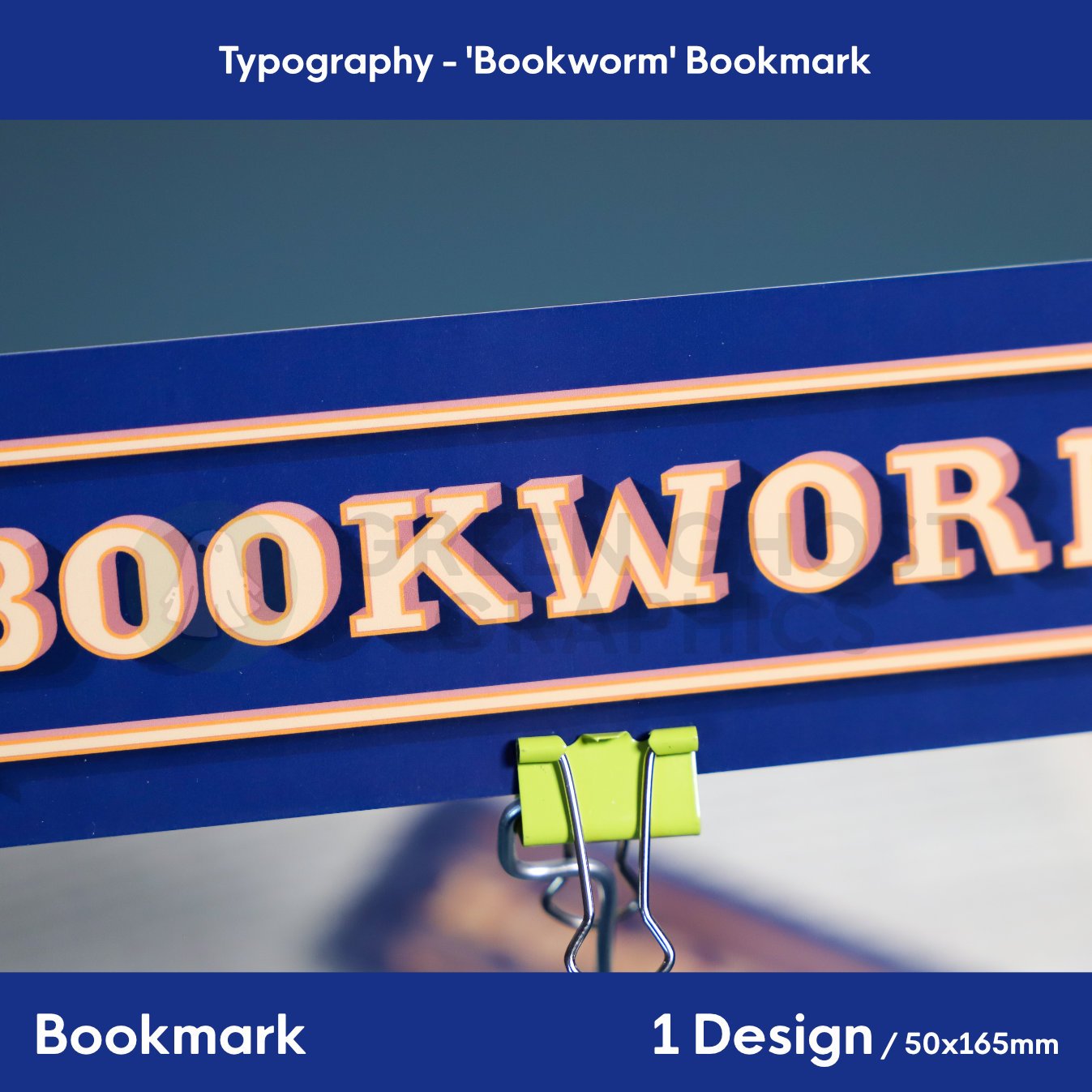 Close up of rectangular bookmark with rounded edges. Dark blue background with custom pale beige text reading 'bookworm', shown against a blurred book background.