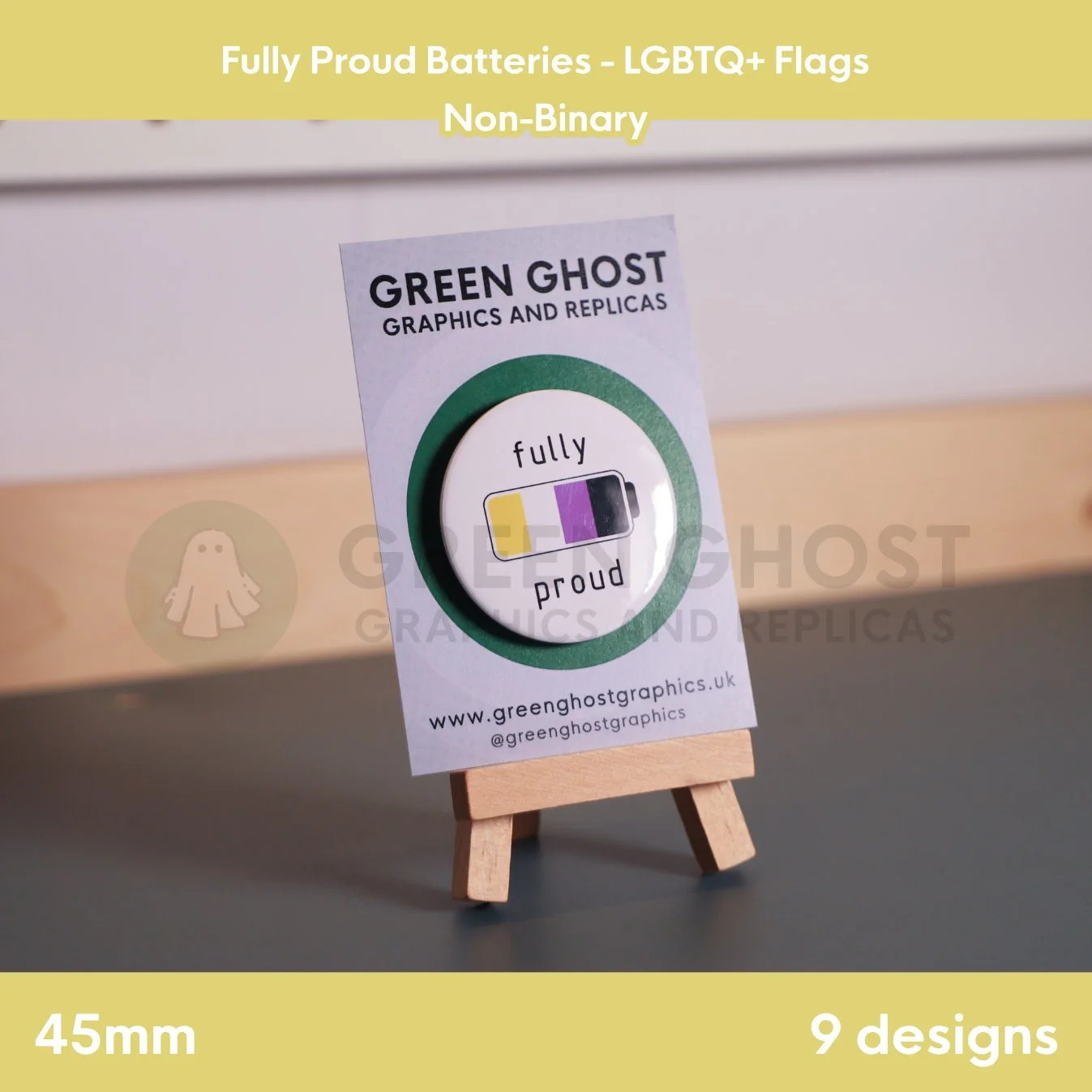 A round badge with a yellow, white, purple, and black battery design displayed on a branded backing card on a wooden easel.