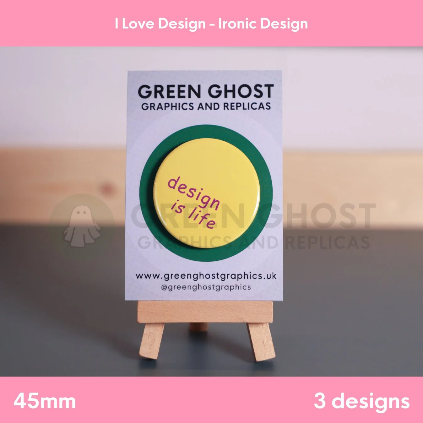 A round yellow badge with purple “design is life” text mounted on a branded card on a wooden easel.