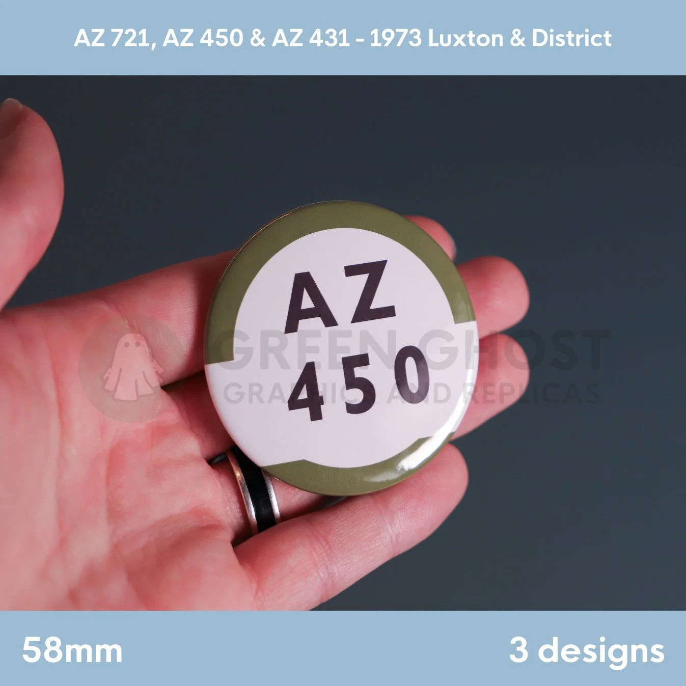 A round white badge with a green outer ring and the text “AZ 450” held in a hand against a dark backdrop.