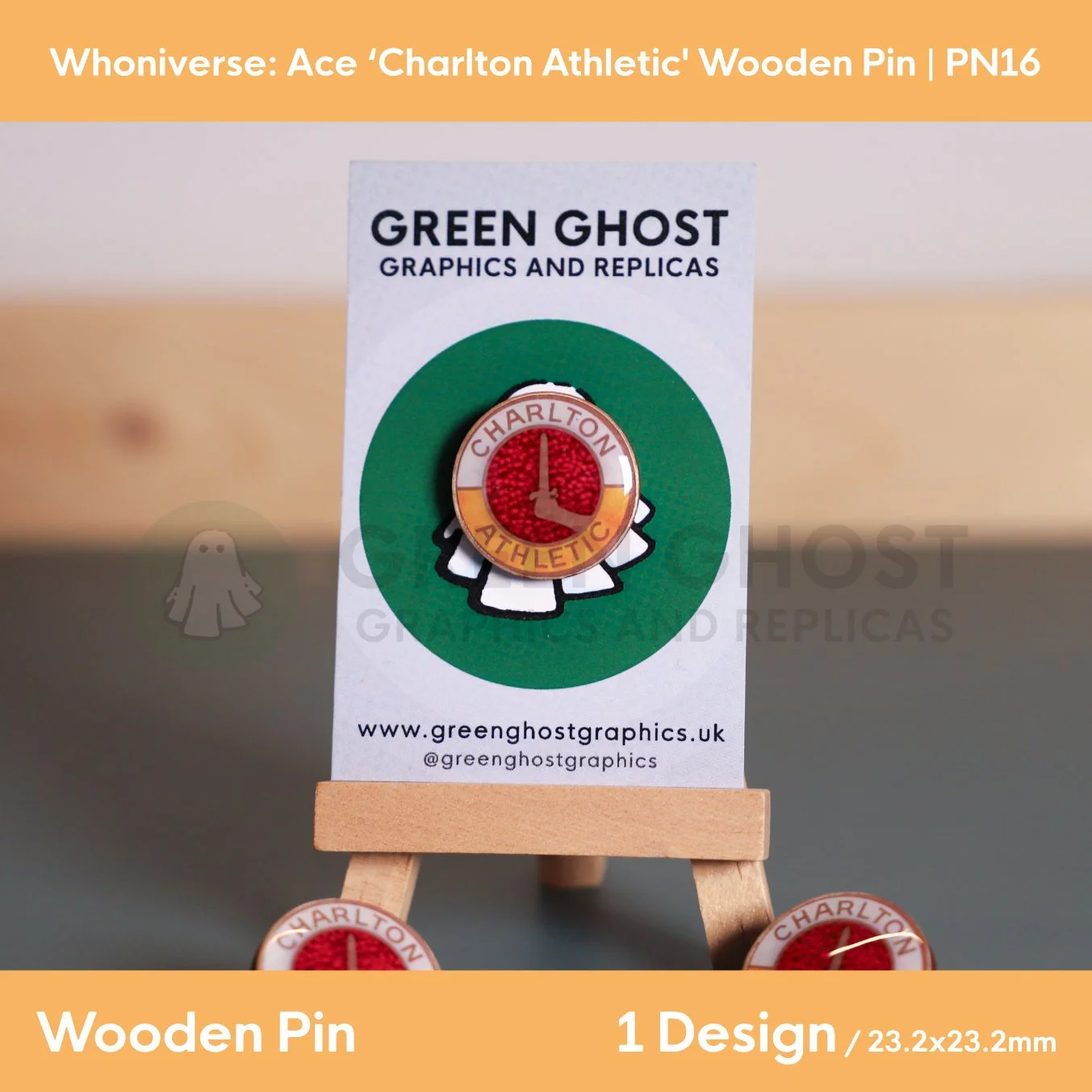 A circular wooden “Charlton Athletic” pin with a red textured centre and gold border, mounted on a branded backing card on a small wooden easel.