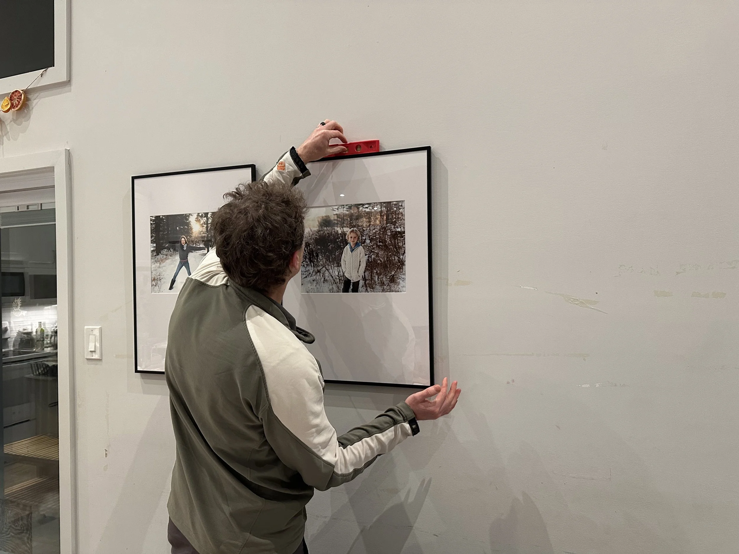 Man hanging up professional family photos on his walls using ikea frames and command strips.