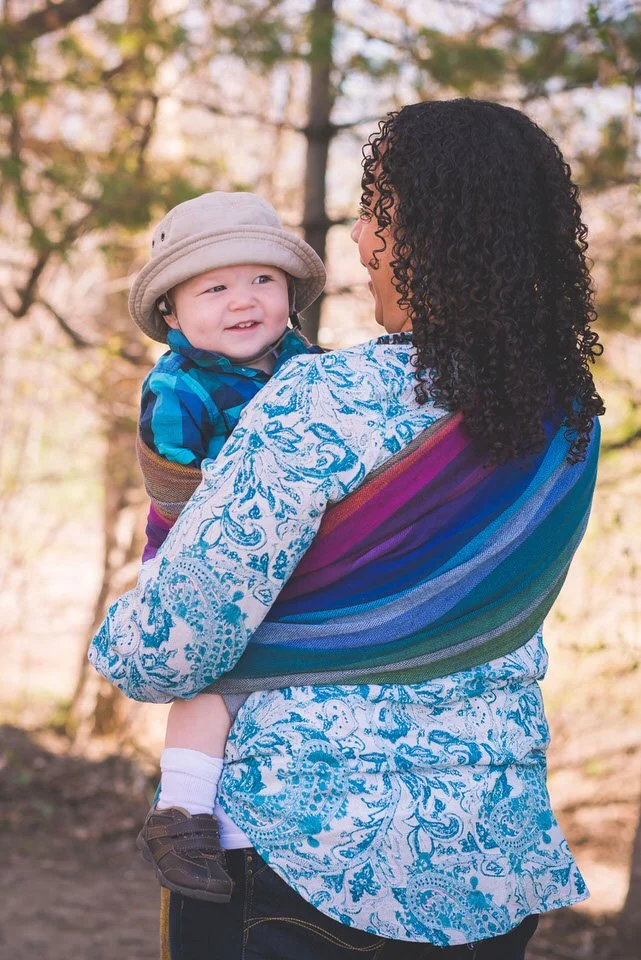 Mom carrying baby in rainbow Girasol Wrap in the forest near Ottawa.