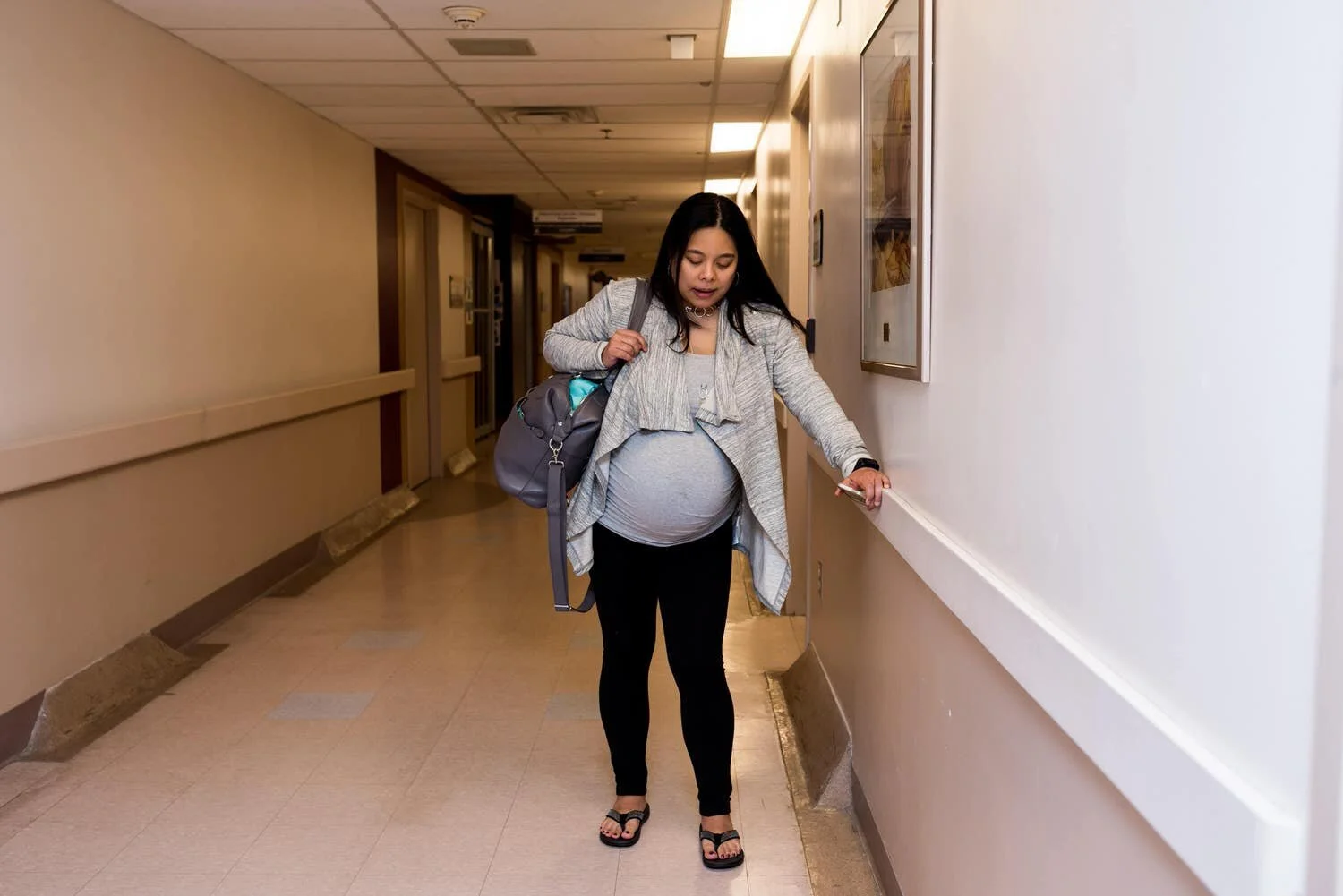 Beautiful woman in labour having contractions in the civic hospital hallway at birthing unit.