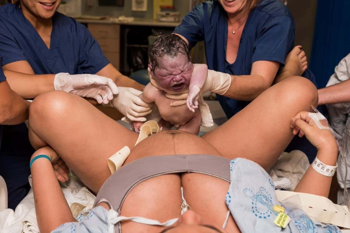 Newborn baby being born and landing in mom's arms. He is beautiful.