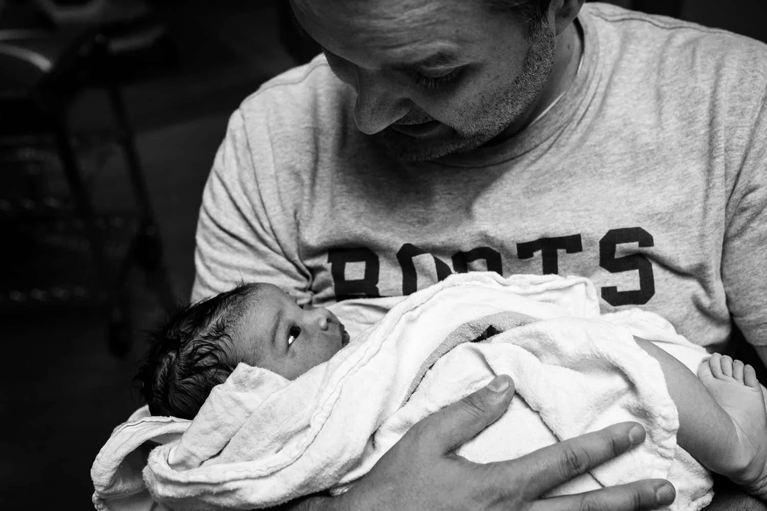 Dad holding his newborn son looking at each other in the eyes.