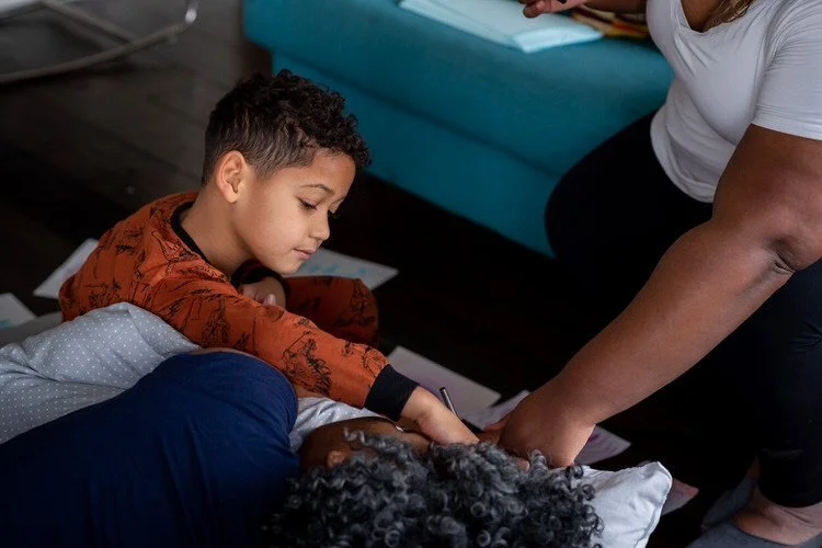 Young son and aunt support mom who is in labour in her family room at home. The photo is very loving.