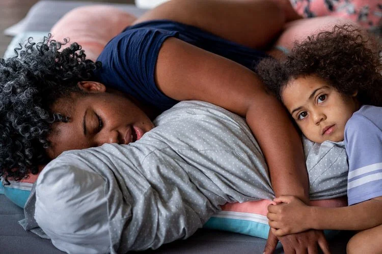 Daughter is holding her mom's hand while mom is in labour at home. Her baby sibling will be born soon.