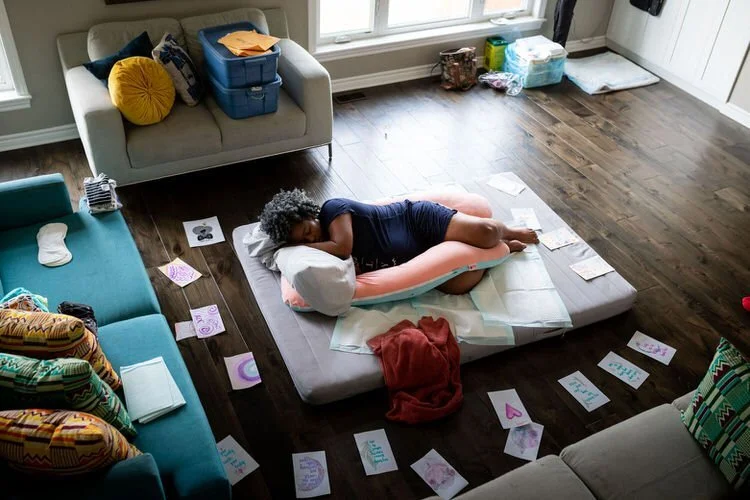 Mom resting during homebirth on floor surrounded by loving notes and affirmations.