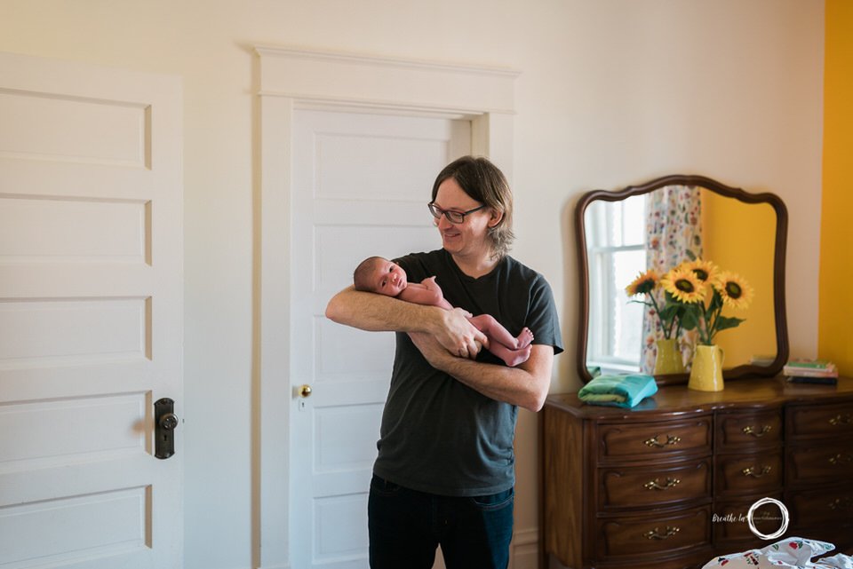 Dad holding baby son at home.