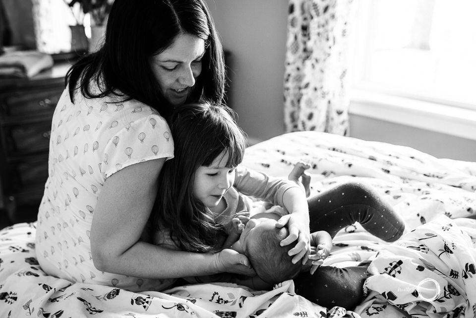Big sister getting to know her newborn baby brother with Mom.